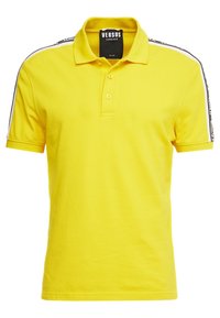 Polo jaune en coton, doté d'un col classique, d'une patte de boutonnage à deux boutons, et de bandes latérales noires et blanches avec un détail logo.