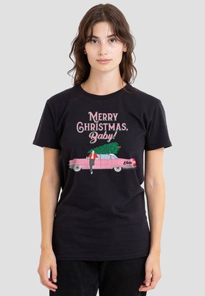 Young woman wearing black t-shirt with "Merry Christmas, Baby!" text and graphic of pink car carrying Christmas tree and running man.