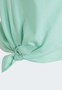 Mentolová košile s uzlem na spodním lemu. Vyrobena z měkkého materiálu, má volný střih a čisté švy.
