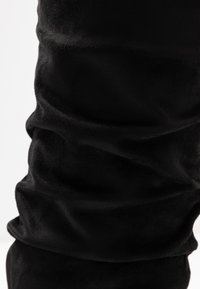 Black, soft fabric with a velvety texture; features gathered detailing for a ruched appearance, showcasing curves and depth.