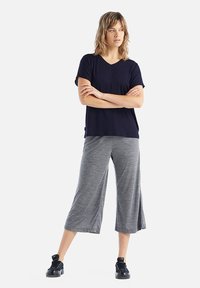 T-shirt con scollo a V blu navy abbinato a culotte grigie, realizzata in tessuto morbido. Presenta maniche corte e una vestibilità ampia. Indossato con sneakers nere.