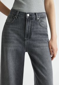 Hoge taille zwarte denim jeans met een rechte pijp, lichte slijtage en een klassiek vijf-pocket ontwerp met zilveren accenten.