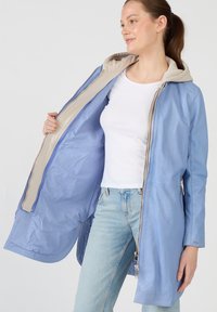 Vaaleansininen vetoketjullinen takki, jossa on beige huppukangas, sileä pinta, slim fit ja sivuvetoketjulliset taskut.