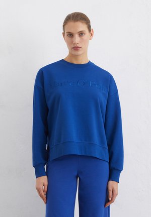 Blaues Sweatshirt mit Rundhalsausschnitt, ausgestattet mit dem erhabenen Markennamen "Marc O'Polo" auf der Vorderseite. Der Pullover hat einen lockeren Schnitt und gerippte Bündchen.