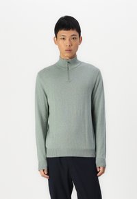 Light green quarter-zip sweater made of soft fabric, featuring long sleeves and ribbed cuffs and hem. Smooth texture with a fitted design.
