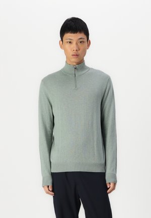 Pulover verde deschis cu fermoar pe jumătate, confecționat dintr-un material moale, având mâneci lungi și manșete și tiv cu nervuri. Textură netedă cu un design ajustat.