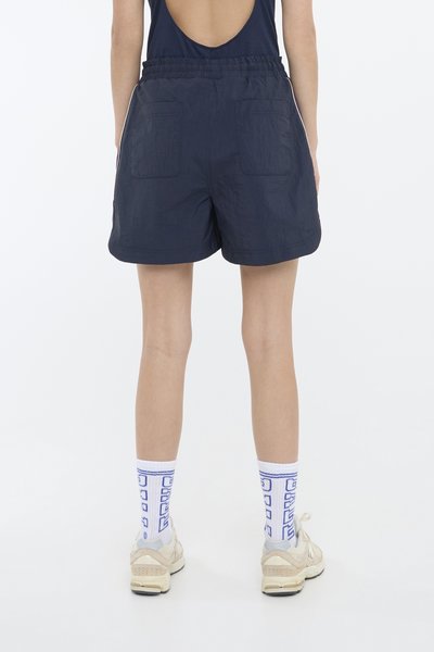 Mørkeblå shorts med elastisk liv, to baklommer og teksturert stoff. Brukt med hvite sokker med blå geometriske mønstre og joggesko.