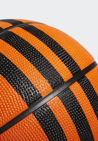 Pallone da basket con una superficie arancione e strisce nere testurizzate. Il design include punti in rilievo e una cucitura in gomma nera per una presa migliore.