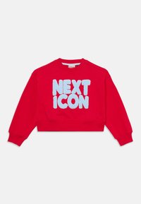 Červená skrátená mikina z bavlny s nadýchaným, svetlomodrým nápisom "NEXT ICON" vpredu. Rybované manžety a výstrih.