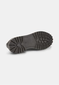 Semelle extérieure en caoutchouc noir avec de profondes rainures et motifs de traction, présentant une surface lisse et des bords arrondis pour plus de durabilité.