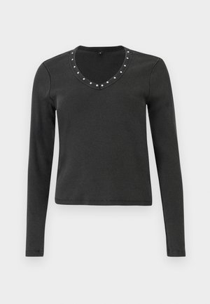 Črn zgornji del z dolgimi rokavi z rebrasto teksturo, ki ima V-izrez okrašen s srebrnimi bleščicami okoli izreza.