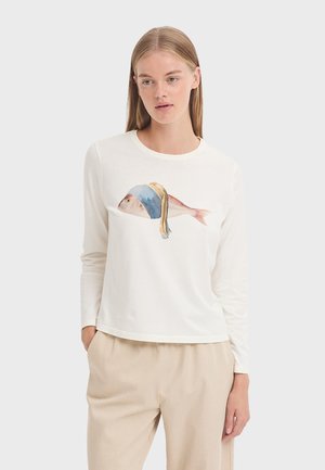 Long-sleeve white T-shirt featuring a colorful fish graphic with a blue headscarf. Soft fabric and relaxed fit. Worn with beige pants.