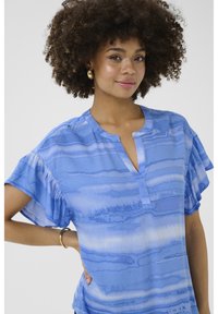 Zila blūze ar V-veida kakla izgriezumu un volānu īsām piedurknēm. Iekļauj teksturētu rakstu ar dažādām zilu un baltu svītru nokrāsām.