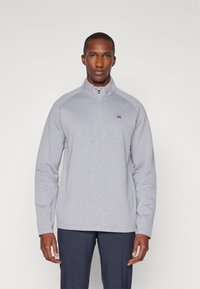 Lys grå zip-up fleecegenser med lange ermer, med høy krage og logo på venstre bryst; glatt tekstur og avslappet passform.