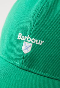 Boné de beisebol verde em algodão com logo branco bordado "Barbour" e design de escudo. Tecido texturizado, aba curvada.