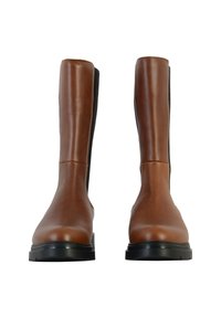 Par de botas de cuero marrón a media pantorrilla con paneles laterales de elástico negro y suelas de goma negra gruesa, vistas de frente sobre un fondo blanco.