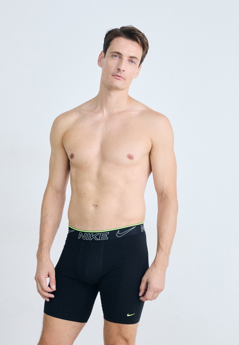 Zwarte Nike boxershorts met een neon groene tailleband en logo, met een strakke pasvorm en gladde stof, ontworpen voor comfort en ondersteuning.