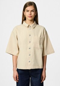 Bežna oversized kratka majica s kratkimi rokavi, izdelana iz teksturirane tkanine, z ovratnikom, sprednjim žepom in srebrnimi pritisnimi gumbi po sredini.
