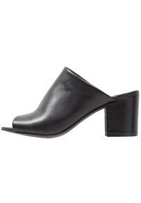 Zwarte leren open teen mules met een strak ontwerp, voorzien van een chunky blokhak en een gladde textuur, die minimalistische styling benadrukken.