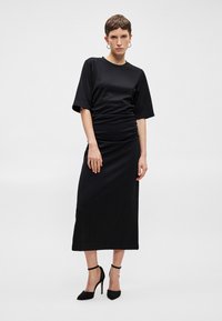 Μαύρο midi φόρεμα με κοντά, φαρδιά μανίκια και ραφή στη μέση. Λείο ύφασμα με σφιχτή σιλουέτα και στρογγυλή λαιμόκοψη.