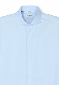 Hellblaues kurzärmliges Hemd mit strukturiertem Muster, knopfähnlichem Verschluss, softem Kragen und gesticktem Logoetikett nahe dem Hals.