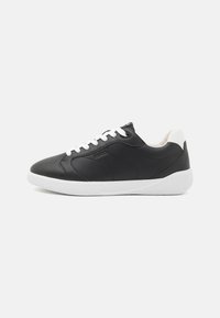 Black leather sneaker with white rubber sole, round toe, and lace-up front. Features subtle stitching details on the upper.