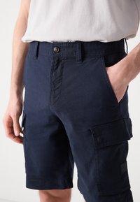 Námornícky modré cargo šortky vyrobené z bavlnenej zmesi. Majú bočné vrecká, predné zapínanie na gombík a bežný strih.