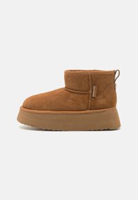 Botine din suede maro, cu vârf rotunjit, cu un șpațiu joasă și talpă cu platformă groasă; prezintă un tab de prindere în spate și detalii de cusătură.