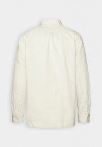 Chemise à manches longues blanc cassé vue de dos, avec un unique pli au dos et des poignets boutonnés.