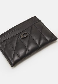 Tarjetero de cuero negro con textura acolchada, que cuenta con cinco ranuras para tarjetas y un acento de logo metálico en el frente. Diseño compacto.