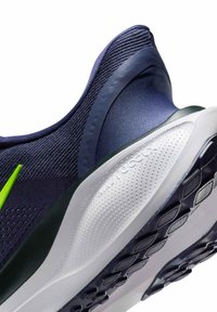 Scarpa da ginnastica blu scuro con accenti verdi, tomaia in tessuto testurizzato, suola imbottita bianca e suola in gomma tassellata per aderenza.