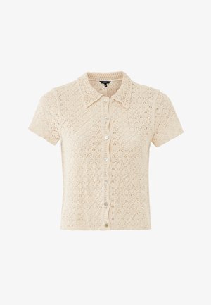 Chemise beige à manches courtes en crochet avec col et motifs floraux, tissu léger et semi-transparent.