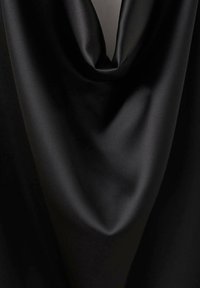 Čierny saténový materiál s hladkou textúrou, jemne splývajúci v voľnom, kaskádovom tvare. Materiál vyzerá lesklo a luxusne.