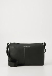 Mustast nahast risti üle keha kantav kott lukuga sulgemise, reljeefse logoga, lamedapinnalise esiosa ja reguleeritava rihmaga. Sile tekstuur ja minimalistlik disain.