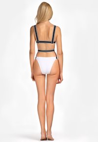 Czarny i biały pasek bikini z szerokimi ramiączkami, połączony z białymi majtkami w stylu high-waisted, eksponującymi gładką teksturę i minimalny design.
