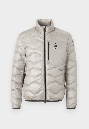 Svetlo siva prešita puhovka z visokim ovratnikom, zadrgo čez cel sprednji del, zip žepom na prsih in stranskima žepoma z elastičnimi manšetami in spodnjim robom.