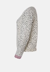 Strickpullover in Creme mit schwarzen Punkten, zum Einsatz mit rosa Akzenten an den Ärmelabschlüssen. Gerippter Saum und weiche Textur. Seitenansicht.