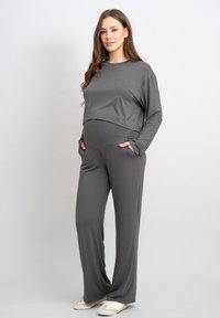 Set da salotto grigio con maglia a maniche lunghe dal taglio comodo e pantaloni con tasche laterali. Realizzato in materiale morbido e elasticizzato.