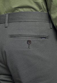 Herren-Hosenträger in Dunkelgrau mit glattem Stoff, einer knöpfbaren Gesäßtasche und einem dezenten Polo-Logo. Tailored Fit mit Gürtelschlaufen.