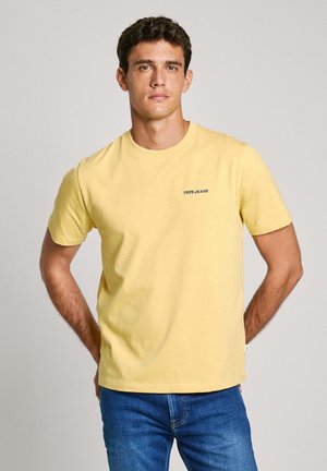 Yellow cotton t-shirt with short sleeves, round neck, and a small blue "PEPE JEANS" logo on the chest. Worn with blue jeans.