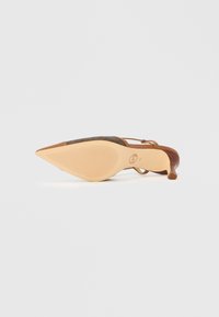 Čevlji s peto in špičastim prstom, z rjavim usnjenim trakom, teksturirano površino in gumijastim podplatom s horizontalnimi žlebovi za oprijem.