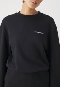 Μαύρο φούτερ από μαλακό ύφασμα, με στρογγυλή λαιμόκοψη και μικρό λευκό λογότυπο "KARL LAGERFELD" στο στήθος.