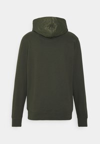 Sweat-shirt vert foncé à manches longues avec capuche matelassée, vu de dos sur un fond clair uni.