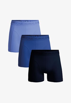 Tri pánske boxerky v svetlomodrej, strednom modrom a tmavomodrom odtieni s páskami na pásoch so značkou „MUCHACHOMALO“.