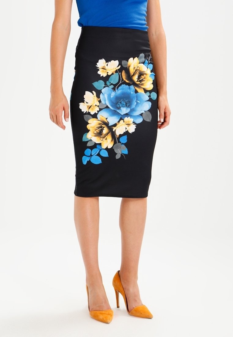 Gonna a matita nera con vivaci stampe floreali blu e gialle. Ha un design aderente ed è abbinata a tacchi alti arancioni.