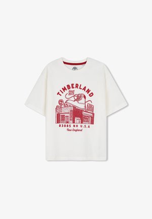 Biała koszulka z krótkim rękawem z czerwonym grafiką buta na budynku sklepu oraz napisem Timberland Since 1973 New England.
