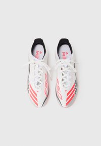 Scarpe da ginnastica bianche con accenti rossi e neri, caratterizzate da un design elegante, lacci e una texture leggera. Marcate con il logo "E50".