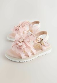 Różowe sandały z wieloma kwiatami z tkaniny i złotymi akcentami. Miękkie paski i biała, teksturowana podeszwa zapewniają wsparcie i styl.