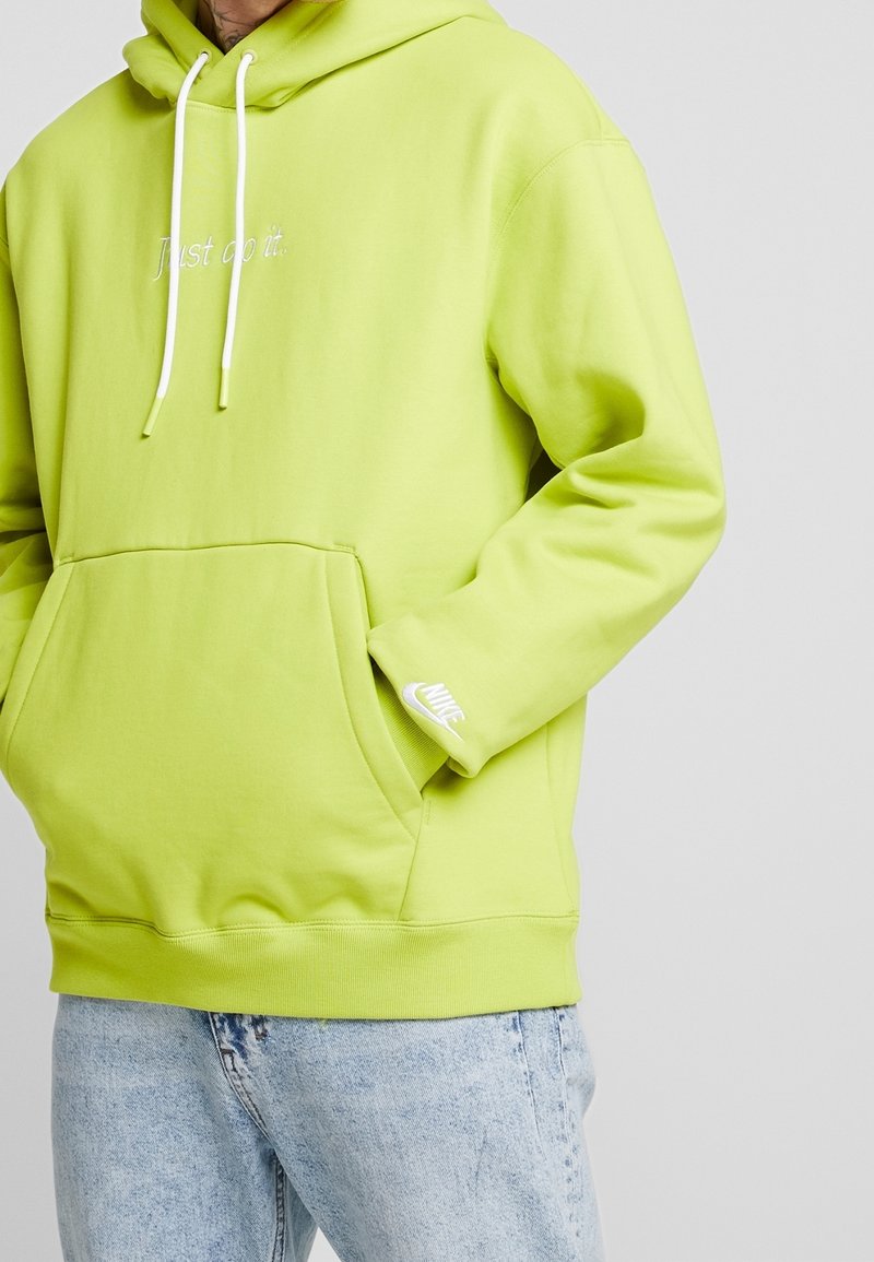 Limonková mikina s kapucí a přední kapsou, bílé šňůrky a vyšívané logo "Just do it."; má malé bílé logo Nike na manžetě.