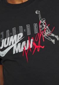 Camiseta de algodón negra con un gran estampado gráfico, texto en plata y rojo, y la silueta de un jugador de baloncesto en acción.